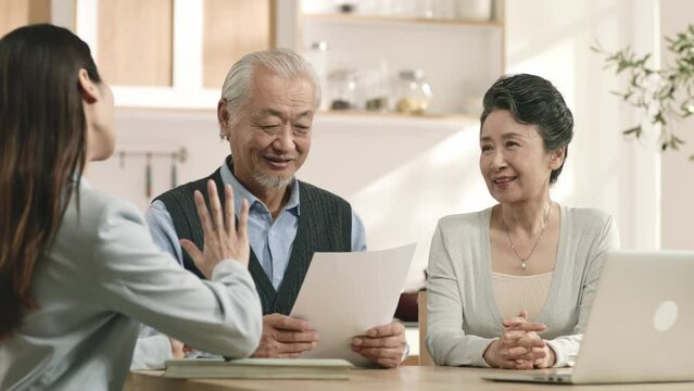 senior asian couple appears to be convinced by saleswoman and is happy to sign contract