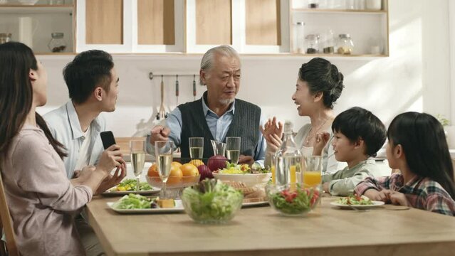 three generation happy asian family eating meal and enjoying reunion at home