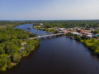 Fototapeta na wymiar Aerial shot view of a highway bridge and swing bridge at Milton, Florida. Road bridge over the wide river waterway in the middle of two lands with tall trees on left and buildings on right.