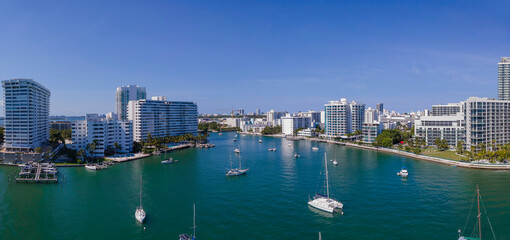 Fototapeta na wymiar Boats on the blue intracoastal waterway between modern buildings in Miami Beach, Florida. Aerial panoramic view of coastline multi-storey buildings in an intacoastal area.