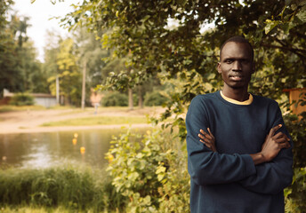 Naklejka na ściany i meble A young black man is walking in the park.