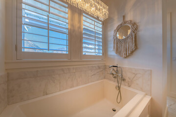 Bathtub with chandelier lights and decorative mirror on the wall. Bathtub with wall-mounted faucet...