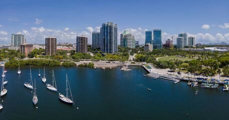 Fototapeta na wymiar Dinner Key Marina and Coconut Grove Sailing Club on a sunny day in Miami Florida. Aerial view of boats anchored at sea with beautiful city skyline and blue sky in the background.