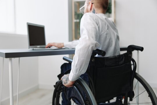 A Man Wheelchair Businessman With Tattoos In The Office Works At A Laptop Online, Business Process, A Wheelchair Close-up, Integration Into Society, The Concept Of Working A Person With Disabilities