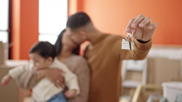 Couple and son hugging each other holding keys at new home