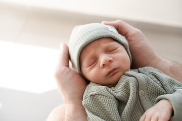 Close up of caucasian hairy brunet cute newborn baby sleeping.One or two week child in male hands.Unrecognizable man, father,holding child.Care,love,happiness concept. - obrazy, fototapety, plakaty