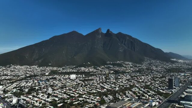 Aerial view over the Monterrey cityscape with the Cerro de la silla mountain in the background, in sunny Mexico