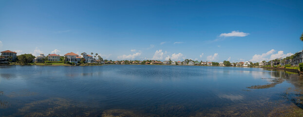 Fototapeta premium Clean reflective Four Prong Lake waterfront at Destin, Florida. Panorama of neighborhood with lakefront views and clear sky background.