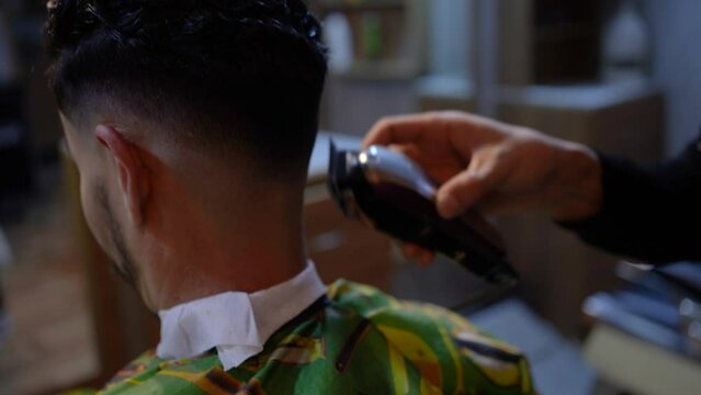Hairdresser cutting young guys hair with a machine