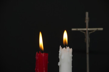 Two burning candles and Christian cross in the darkness