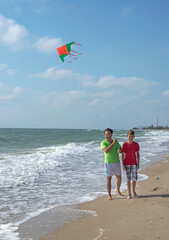 Leisure. Rest of parents with children. Dad and son fly a kite near the sea.