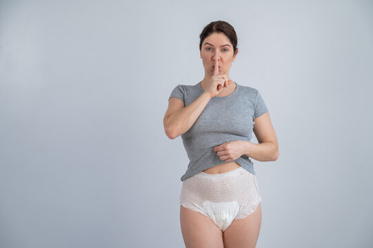 The woman is wearing adult diapers. Urinary incontinence problem. Finger on  lips - silent gesture. Stock Photo
