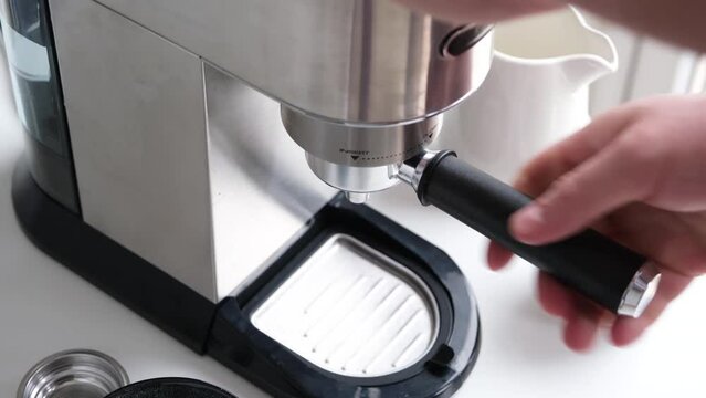 male hands holding portafilter and making fresh aromatic coffee at home
