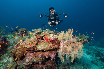 Male scuba diver with camera taking a photo with beautiful coral reef and marine life at North...