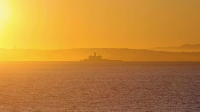 A prominent landmark of Bugio Fort lighthouse set offshore with some fog in background. big yellow scenery.