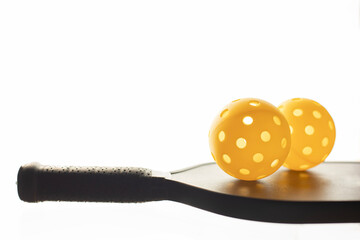 Two pickleballs on the racket