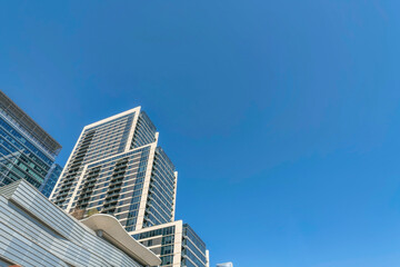 Austin, Texas- View of a layered building with glass exterior from below, Low angle view of a building with modern architectural design against the blue sky background. - obrazy, fototapety, plakaty