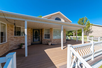 Front exterior of a house with white railings and wooden flooring on the veranda. Home entrance...
