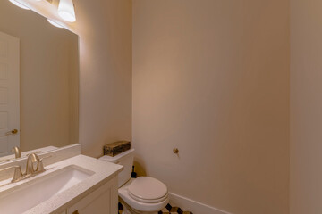 Small bathroom with cream walls and rectangular modern sink. There is a sink on the left with mirror beside the toilet with box near the wall.
