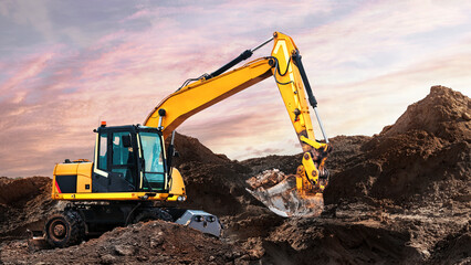 A large yellow wheeled excavator is working in a quarry. Heavy construction hydraulic equipment. excavation. Rental of construction equipment. Development of minerals.