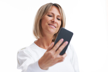 Fototapeta premium Picture of blonde woman over back isolated background with mobile phone