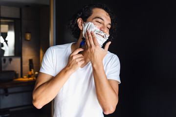 Hispanic serious man shaving his beard at home in Mexico Latin America