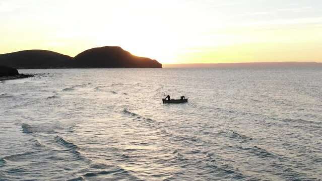Aerial of small fishing boat off shore of Tecolote Beach in Baja Sur, Mexico at sunset