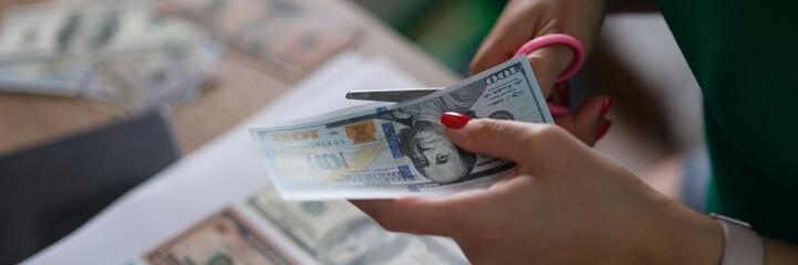 Female hand cuts counterfeit money American dollars