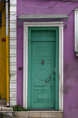 A green door with a white trim in a purple wall.