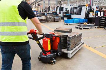 Warehouse worker dragging hand pallet truck or manual forklift with the shipment pallet unloading...