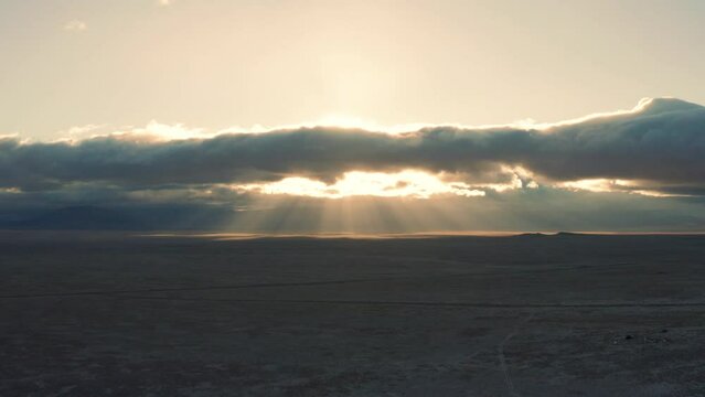 Beautiful god ray sunbeams through clouds over vast desert at sunrise