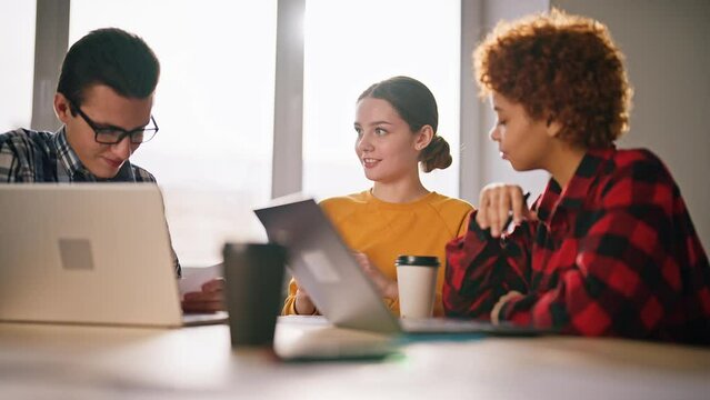 Office workers sit at work in office at table with laptop and solve organizational issues and problems. Discuss action plan, strategy for attracting customers. Teamwork. Advertising, target, logistic.