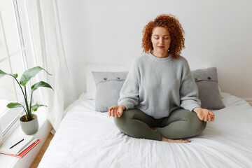Pretty woman practicing yoga at home. Portrait of beautiful redhead caucasian plus-size female with...