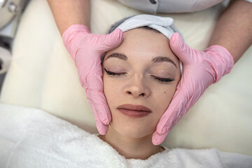 Obraz na płótnie Canvas Closeup of young beautiful woman receiving Anti-aging facial massage in spa center