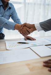 Two young Asian businessmen shake hands and agree to invest in a joint venture related to real...