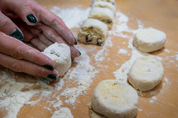 close up of female hand forms a dumpling of cottage cheese dough on a cutting board