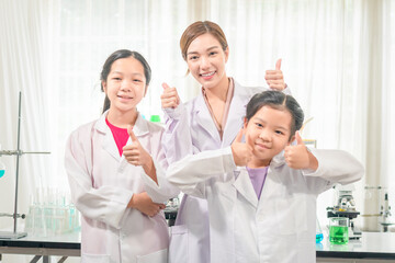 Elementary science class, Cheerful little kids with teacher scientist showing test bottle with chemistry liquid in school laboratory, Science laboratory