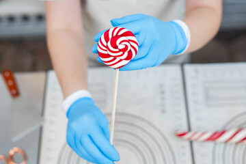 White and red lollipop on a stick in the hands of the cook. Candy. Handmade.