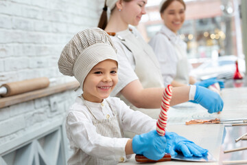 The process of making lollipops in the workshop, a child boy makes caramel.