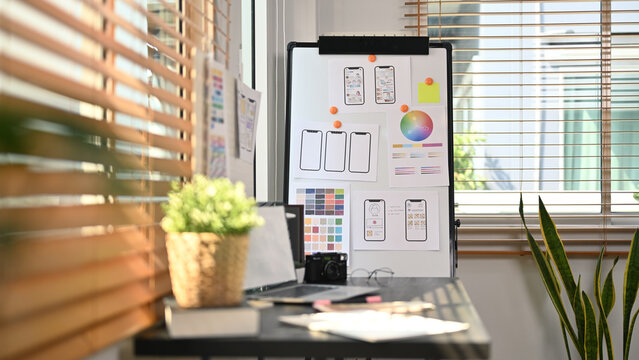 Creative office with laptop, stationery and wireframe sketches of screens for mobile application on a flip board - Powered by Adobe