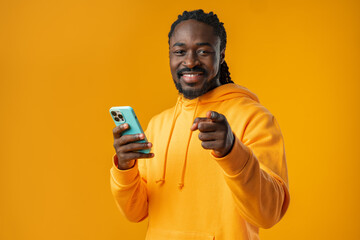 Portrait of handsome african man using his mobile agaist yellow background