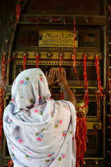 Ajmer Sharif dargah, Rajasthan. Woman touching Sandali gate shrine door. India.