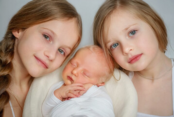 Younger brother. Newborn baby. The girls are holding their newborn brother. Protection. Brother and sisters Family. child in the family. Sisters and younger brother. Baby. The large family. The kid at