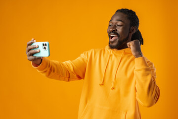 Portrait of handsome african man using his mobile agaist yellow background