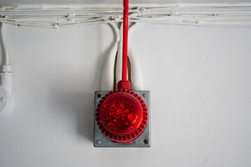 Red fire alarm sounder on a white wall