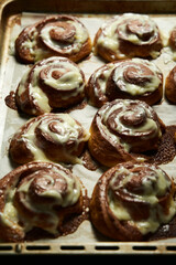 Cinnabon rolls on rustic baking sheet glazed with cream cheese. Freshly baked