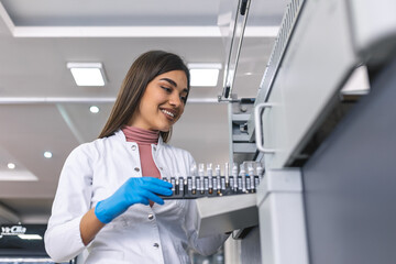 Close-up Female Research Scientist Takes Test Tube with Blood Sample before Putting them Into Medical Analyzing Equipment. Scientist Works in Modern Pharmaceutical Laboratory