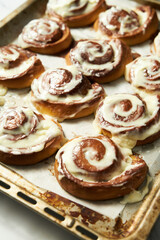 Cinnabon rolls on rustic baking sheet glazed with cream cheese. Freshly baked