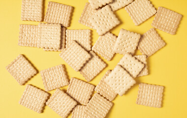 A pile of crackers carelessly scattered on a yellow background close-up