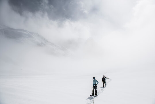 Two climbers on the Ruth Glacier navigating in low visibility conditions.